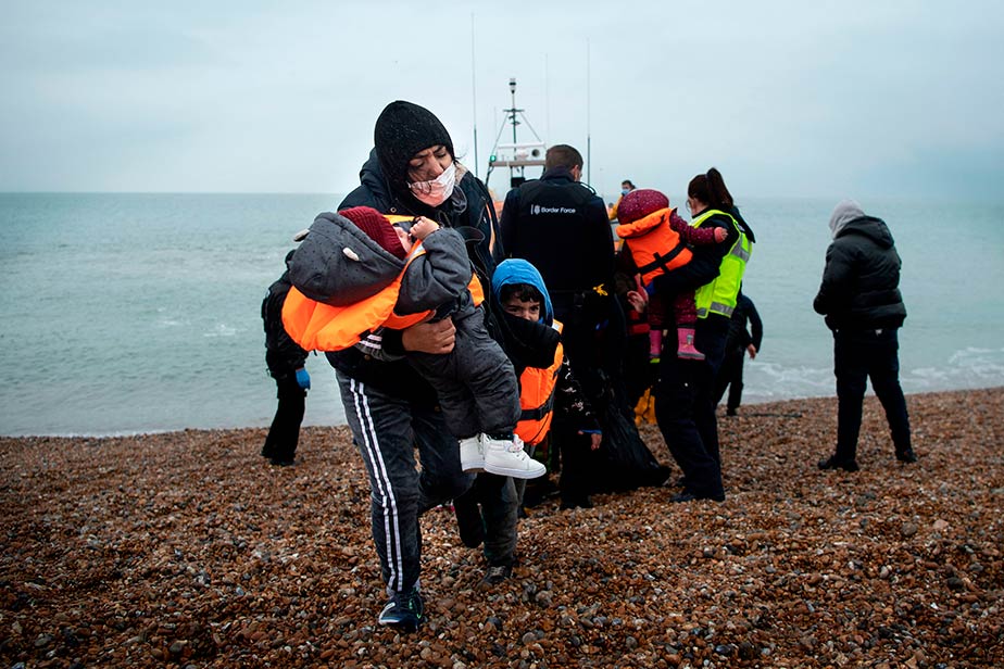 Agotada y después de jugarse la vida en el trayecto del canal de la Mancha, una mujer y sus hijos desembarcan en la playa de Dungeness, en la costa suroeste de Inglaterra. Algunos de los migrantes que la acompañaban en este viaje y que fueron rescatados por el bote salvavidas del RNLI (Royal National Lifeboat Institution) relataron que tuvieron que achicar el agua de su embarcación y que pasaron doce horas a la deriva.