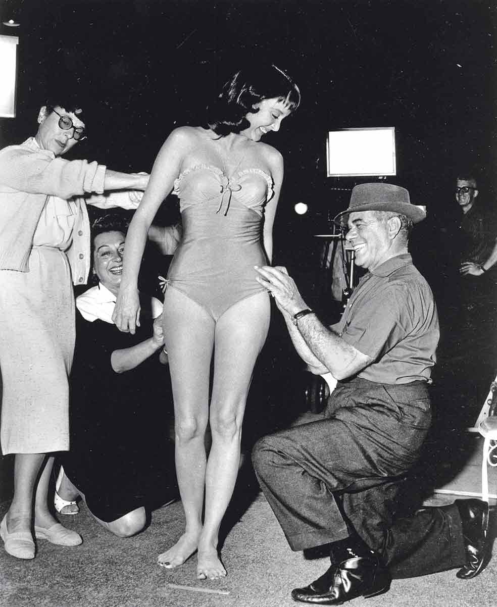 El cine de Capra entusiasmó en los años 30, durante la Gran Depresión, porque insuflaba esperanza. El tiempo, sin embargo, desinfló su éxito aunque las estrellas nunca lo abandonaron. En 1959, dos años antes de dejar el cine, realizó la comedia Un agujero en la cabeza con Sinatra, Edward G. Robinson y Carolyn Jones (arriba en una prueba de vestuario con el director), la futura Morticia de La familia Addams.