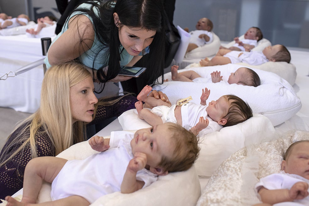 Dos asistentes a la feria de Valencia comprueban la perfección y el detalle de los muñecos Reborn.